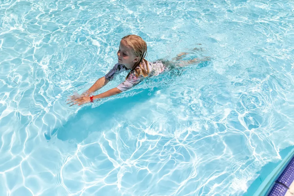 Bambina nuota in piscina riscaldata.